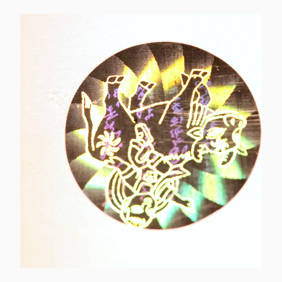 Circular holographic security label showing a radial diffraction pattern shifting through green and gold